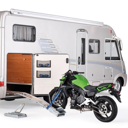 Motorcycle on a trailer attached to a small camper van 